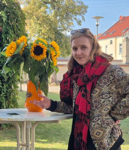 Porträt von Valerie Schönian neben einem Stehtisch mit einer Vase voller Sonnenblumen