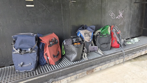 An einer Wand stehen unterschiedliche Fahrradtaschen.