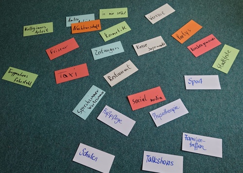 Auf einem grauen Teppichboden liegen verschiedenfarbige Moderationskarten. Darauf haben Teilnehmende geschrieben, wo ihnen "Stammtischparolen" begegnen, z.B. Sport, Fußpflege, Schulen