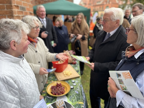 Vier Menschen an einem Infostand: Der Bundespräsident hat das Lern- und Malbuch "Unser Bistum ist bunt" in der Hand.