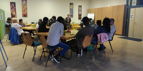 Menschen an Tischgruppen in einem Raum