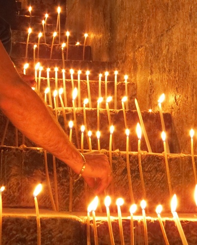 Auf einer Steintreppe stehen lange, brennende Kerzen.