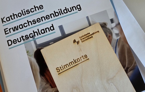 Veranstaltungsunterlagen der Katholischen Erwachsenenbildung in Deutschland: Eine Mappe mit Schriftzug und eine Stimmkarte aus Holz.